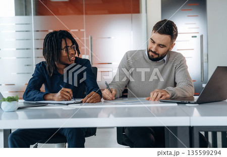 Some paperwork. Two men are in the office Some paperwork. Two men are in the office 135599294