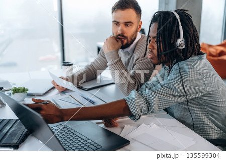 Typing on keyboard of laptop. Two men are working in the office Typing on keyboard of laptop. Two men are working in the office 135599304