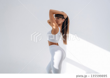 Looking at the camera, posing. Young sportive woman is in the studio 135599895