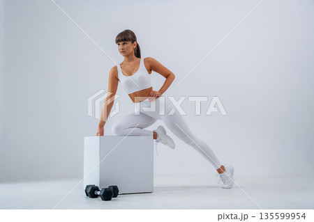 Ready for exercise, dumbbells on floor. Young sportive woman is in the studio 135599954