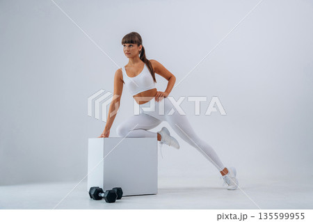 Ready for exercise, dumbbells on floor. Young sportive woman is in the studio Ready for exercise, dumbbells on floor. Young sportive woman is in the studio 135599955