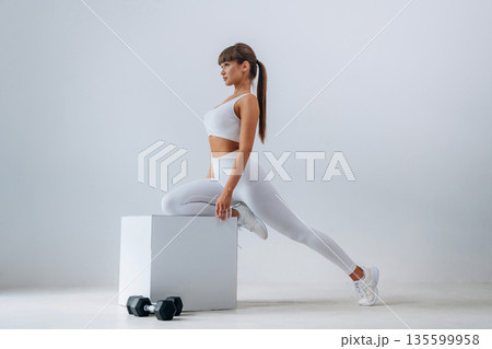 Ready for exercise, dumbbells on floor. Young sportive woman is in the studio Ready for exercise, dumbbells on floor. Young sportive woman is in the studio 135599958