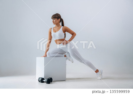 Ready for exercise, dumbbells on floor. Young sportive woman is in the studio Ready for exercise, dumbbells on floor. Young sportive woman is in the studio 135599959