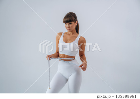 Diet conception, measuring tape. Young sportive woman is in the studio Diet conception, measuring tape. Young sportive woman is in the studio 135599961