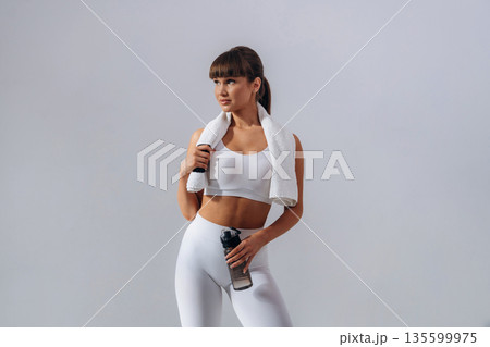Against white wall. Young sportive woman is in the studio Against white wall. Young sportive woman is in the studio 135599975
