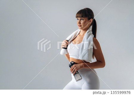Fresh water in bottle. Young sportive woman is in the studio 135599976