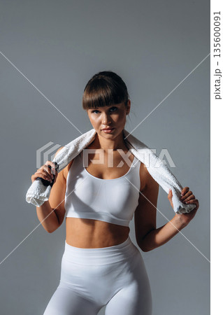 Towel on neck. Young sportive woman is in the studio Towel on neck. Young sportive woman is in the studio 135600091