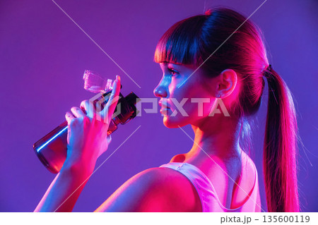 Remember to hydrate, holding bottle of water. Young sportive woman is in the studio Remember to hydrate, holding bottle of water. Young sportive woman is in the studio 135600119