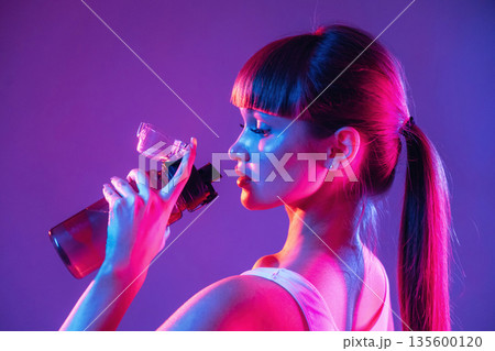 Remember to hydrate, holding bottle of water. Young sportive woman is in the studio Remember to hydrate, holding bottle of water. Young sportive woman is in the studio 135600120