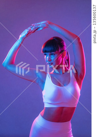 Athletic fitness body type, standing. Young sportive woman is in the studio 135600137