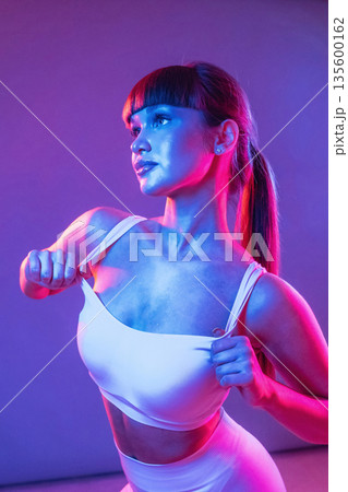 Neon lighting, showing the top. Young sportive woman is in the studio 135600162