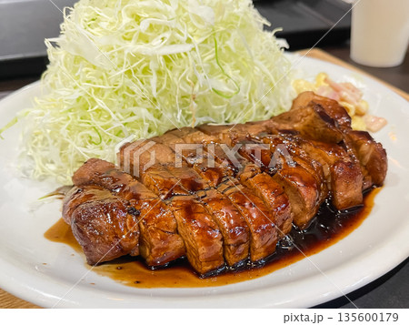 千切りキャベツとトンテキ。甘いタレをかけた豚肉の料理。 135600179