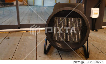 Portable electric space heater on wooden floor in modern interior 135600223