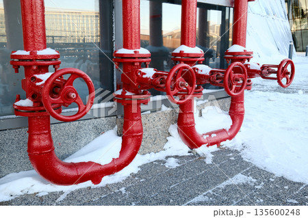 Red industrial gas pipes with valves covered in snow outdoors Red industrial gas pipes with valves covered in snow outdoors 135600248
