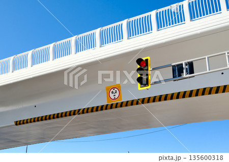 Modern overpass with traffic light and road sign, urban infrastructure, concrete bridge structure against blue sky Modern overpass with traffic light and road sign, urban infrastructure, concrete bridge structure against blue sky 135600318