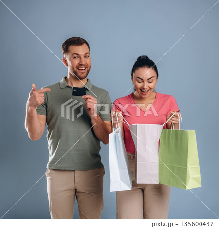 Black colored credit card, with shopping bags. Man and woman are in the studio Black colored credit card, with shopping bags. Man and woman are in the studio 135600437