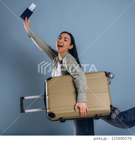 Excited for vacation, with suitcase and documents. Beautiful woman is against background 135600578