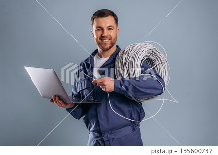 Laptop and internet cables, worker. Handsome man is against background 135600737