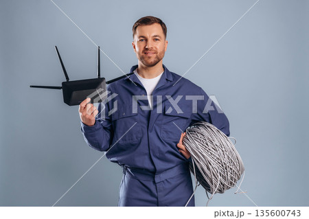 Modern wi-fi router and internet cables. Handsome man is against background 135600743