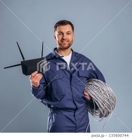 Modern wi-fi router and internet cables. Handsome man is against background Modern wi-fi router and internet cables. Handsome man is against background 135600744