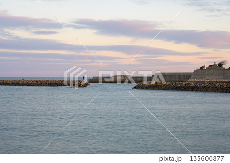 夕焼け空の防波堤で釣りを楽しむ人の風景 135600877
