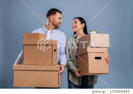 Positive, holding boxes, moving. Man and woman are in the studio Positive, holding boxes, moving. Man and woman are in the studio 135600993