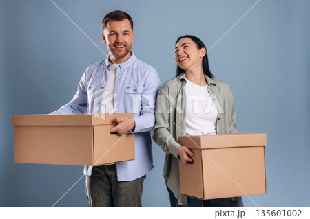 Against blue wall, with boxes, moving. Man and woman are in the studio Against blue wall, with boxes, moving. Man and woman are in the studio 135601002