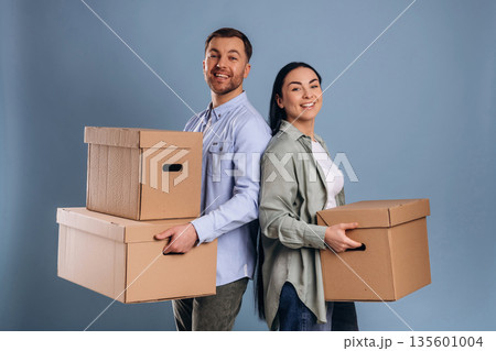 Against blue wall, with boxes, moving. Man and woman are in the studio Against blue wall, with boxes, moving. Man and woman are in the studio 135601004