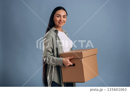 Holding boxes for moving. Beautiful woman is against background Holding boxes for moving. Beautiful woman is against background 135601063