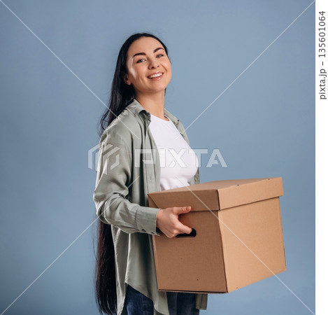 Holding boxes for moving. Beautiful woman is against background 135601064