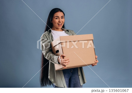 Heavy box, moving concept. Beautiful woman is against background Heavy box, moving concept. Beautiful woman is against background 135601067