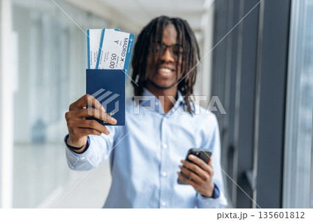 Showing the tickets. Male tourist is in the airport corridor Showing the tickets. Male tourist is in the airport corridor 135601812