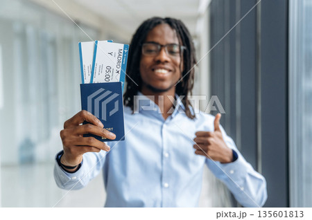 Showing the tickets. Male tourist is in the airport corridor Showing the tickets. Male tourist is in the airport corridor 135601813