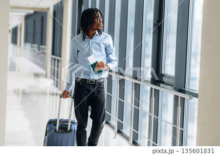 Walking with suitcase. Male tourist is in the airport corridor Walking with suitcase. Male tourist is in the airport corridor 135601831