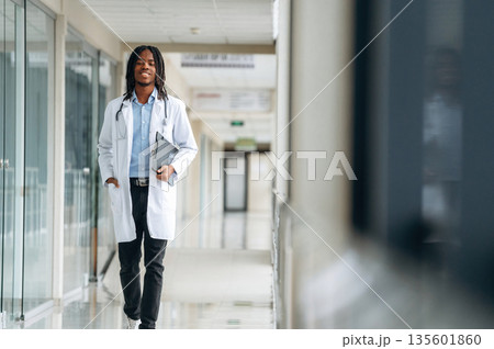 Walking forward. Young male black doctor is in the corridor 135601860
