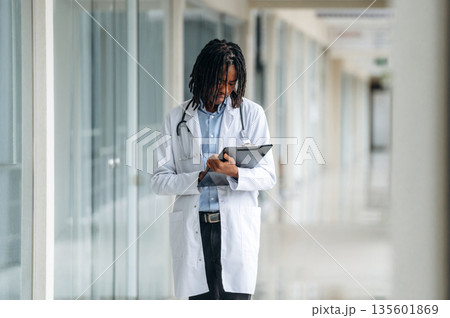 Employee is with notepad. Young male black doctor is in the corridor 135601869