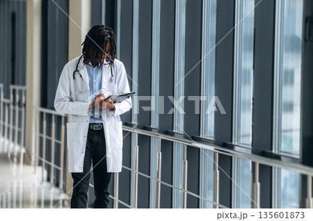 Young male black doctor is in the corridor Young male black doctor is in the corridor 135601873