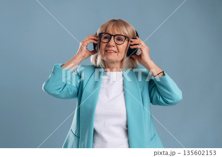 Listening to music, enjoying. Senior woman is against background Listening to music, enjoying. Senior woman is against background 135602153