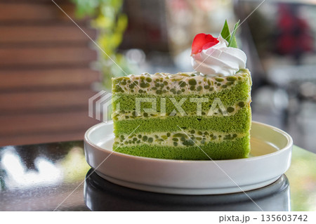 white and green and white Singapore Lod Chong Cake. Decorate with whipped cream. and rose petals placed on banana leaves, on a white ceramic plate on black marble floor, blur nature background, food, 135603742
