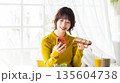 スマートフォンを見ながら食事をする女性 135604738