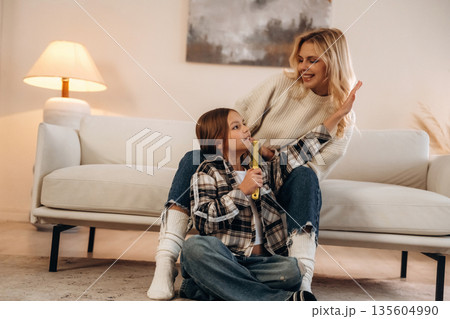 Singing, enjoying free time. Mother and daughter are together in domestic room 135604990