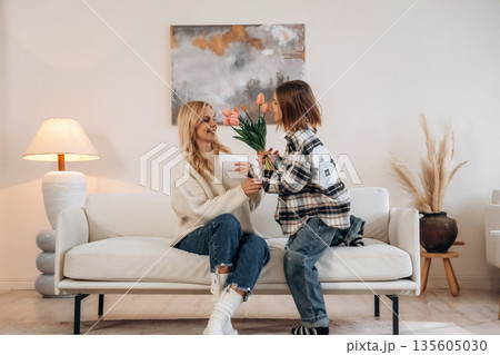 Giving the gift of flowers, holidays. Mother and daughter are together in domestic room 135605030