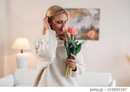 Beautiful young woman is at home with flowers Beautiful young woman is at home with flowers 135605167