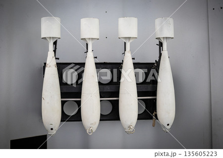 Four white inert training bombs hanging on wall 135605223