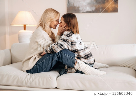 Side view, embracing each other. Mother and daughter are together in domestic room 135605346