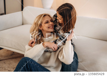 Smiling, having fun. Mother and daughter are together in domestic room Smiling, having fun. Mother and daughter are together in domestic room 135605429