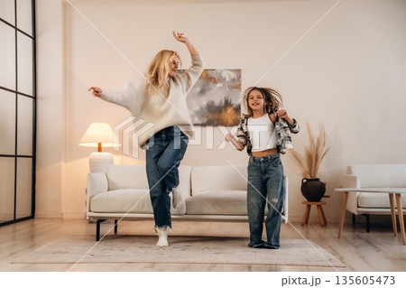 Motion, dancing and having fun. Mother and daughter are together in domestic room 135605473