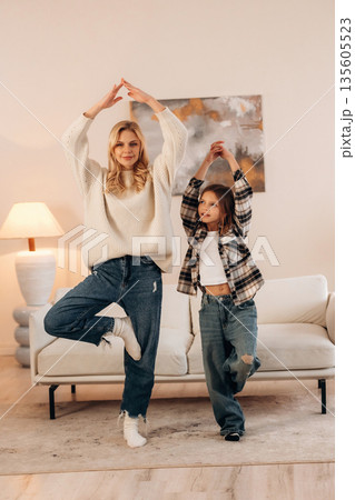 Standing on one leg, sport and yoga. Mother and daughter are together in domestic room 135605523