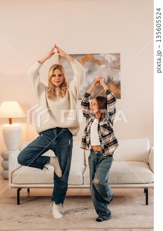 Standing on one leg, sport and yoga. Mother and daughter are together in domestic room 135605524