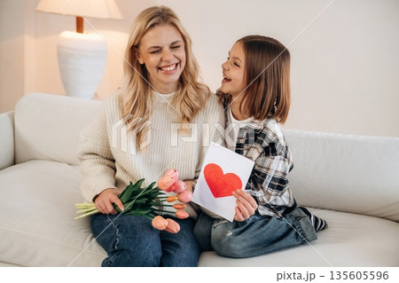 Expression of love at mother's day. Woman and her daughter are together in domestic room 135605596